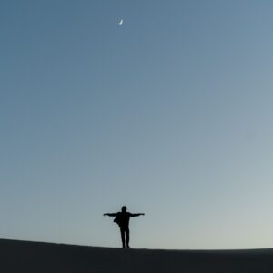 silhouette of person standing on the ground under blue sky during daytime